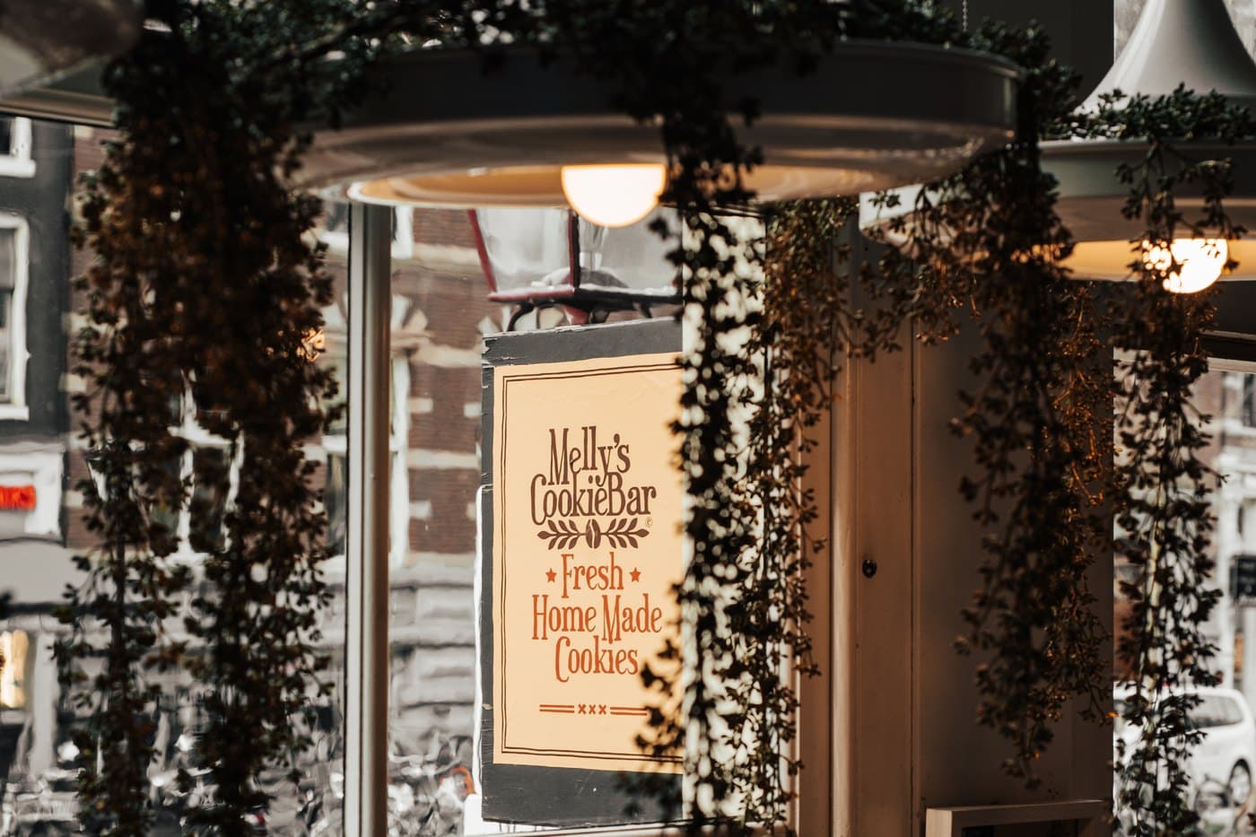The Melly's Cookiebar sign in the window, with an Amsterdam street behind it